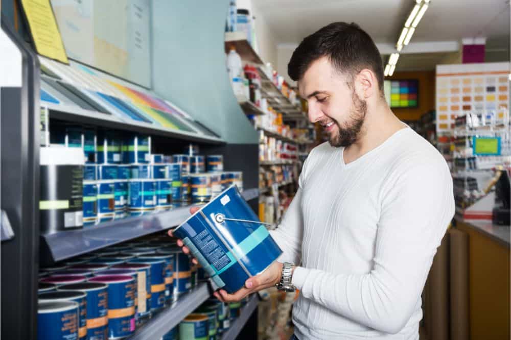 man looking at can of paint