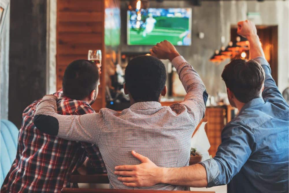 Three men watching football on TV in bar